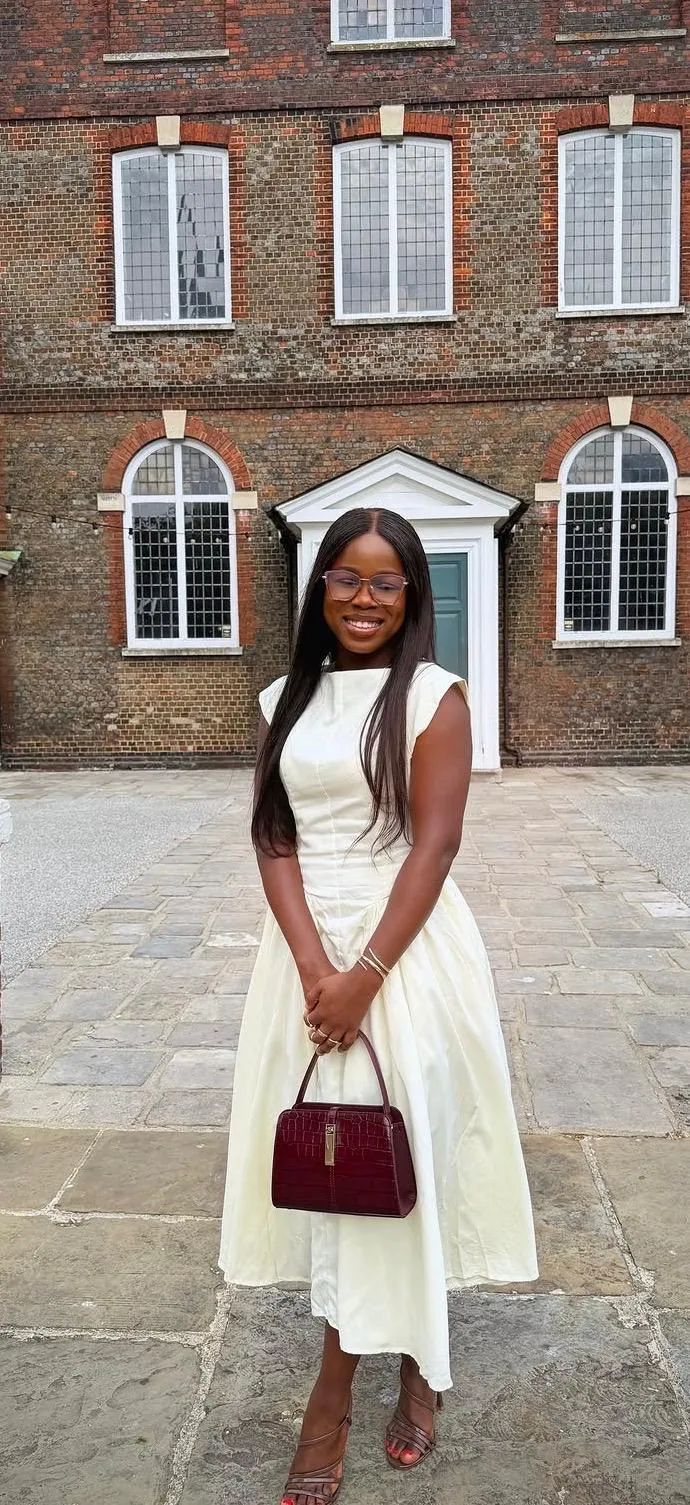 Precious smiling in an ivory dress with a burgundy handbag